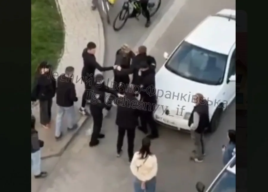 Група людей сперечається біля білого автомобіля