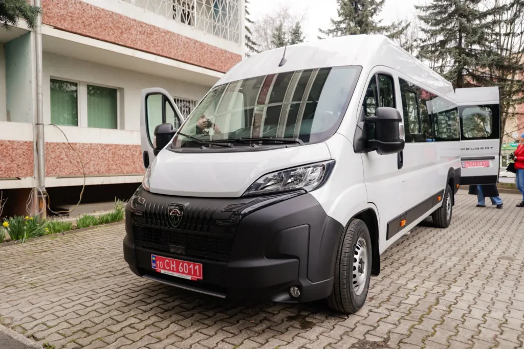 Білий мікроавтобус Peugeot стоїть біля будівлі