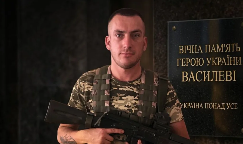 Український військовий біля меморіальної дошки героя