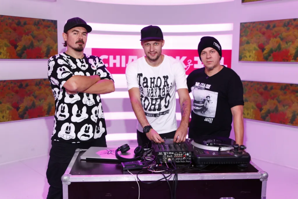 Троє діджеїв біля музичного пульта у студії