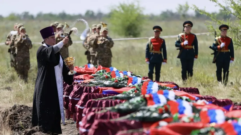 Священник освячує труни на військовому похороні