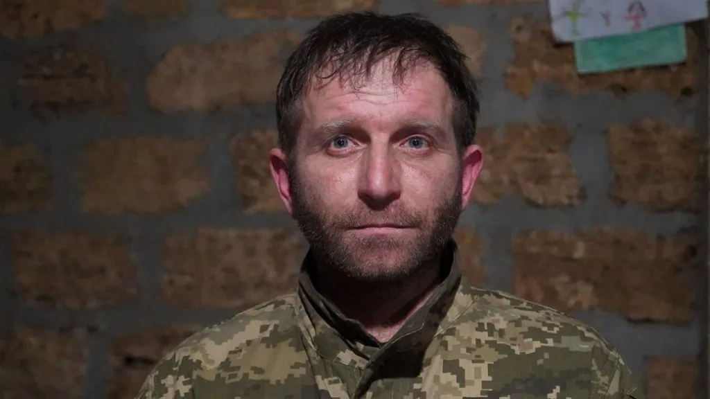 Український військовий у камуфляжній формі перед стіною