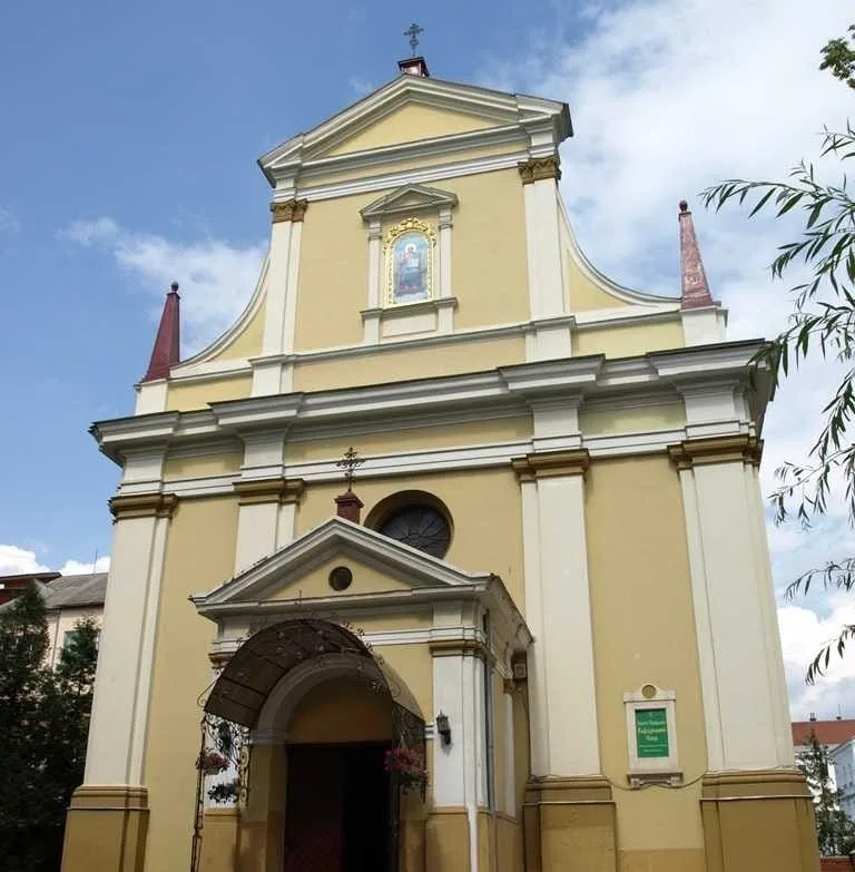 Католицький костел із жовтим фасадом під блакитним небом