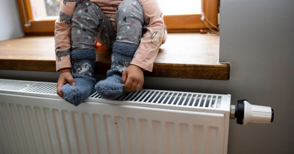 Дитина сидить на батареї в теплих шкарпетках