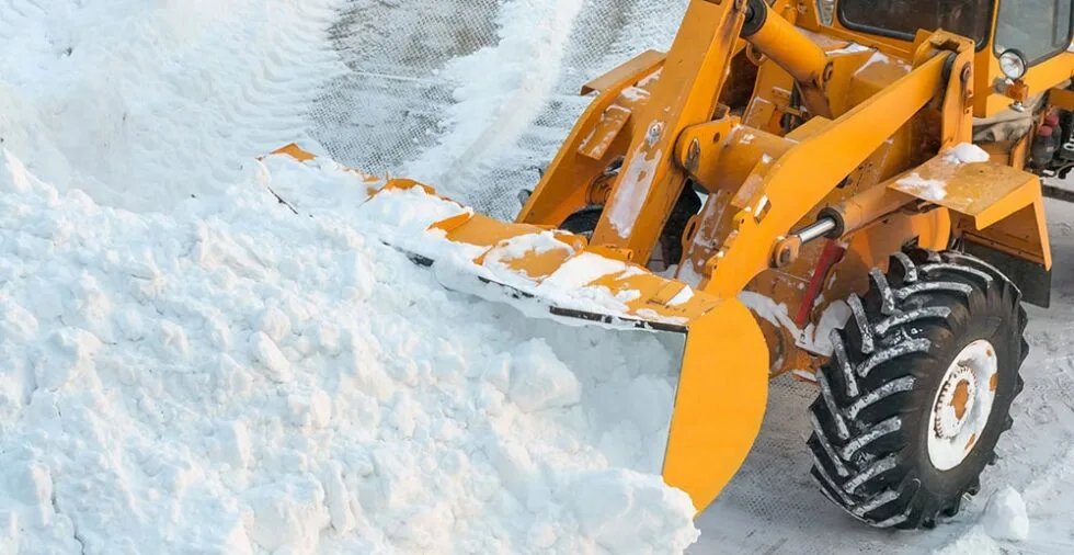 Жовтий трактор розчищає сніг на вулиці