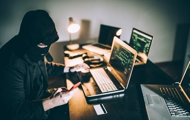 Хакер працює за ноутбуком у темній кімнаті