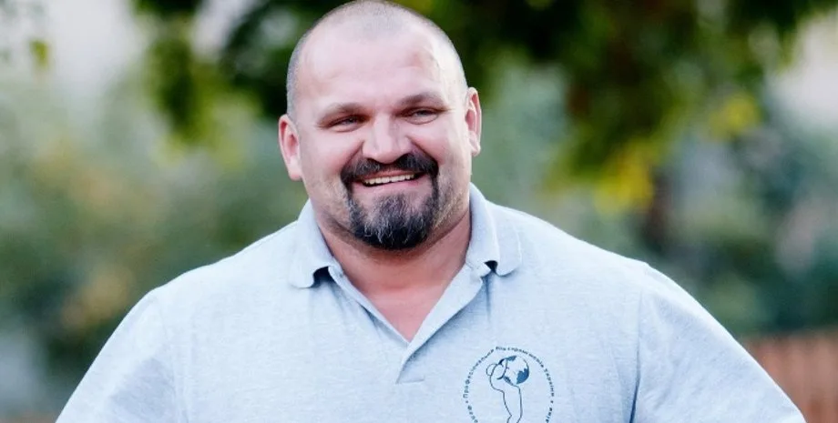 Усміхнений чоловік у сірій футболці на вулиці