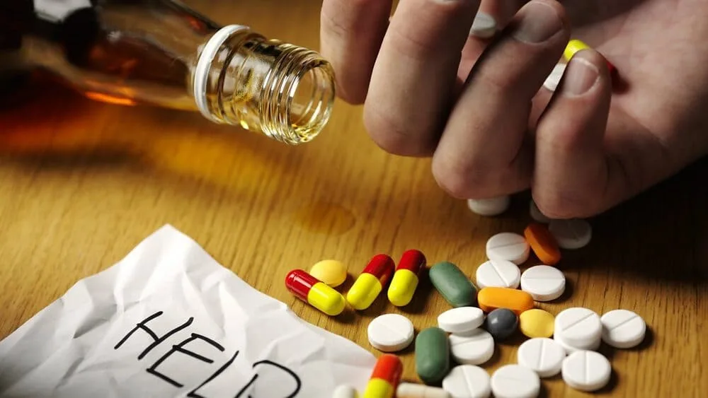 Рука з пляшкою, пігулки та записка допомоги