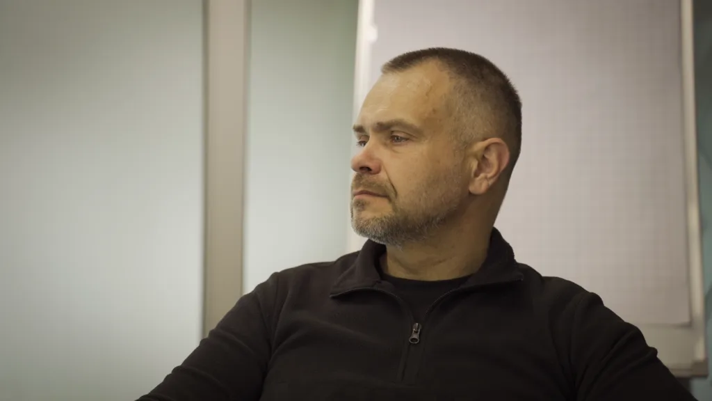 Чоловік у чорному светрі дивиться убік