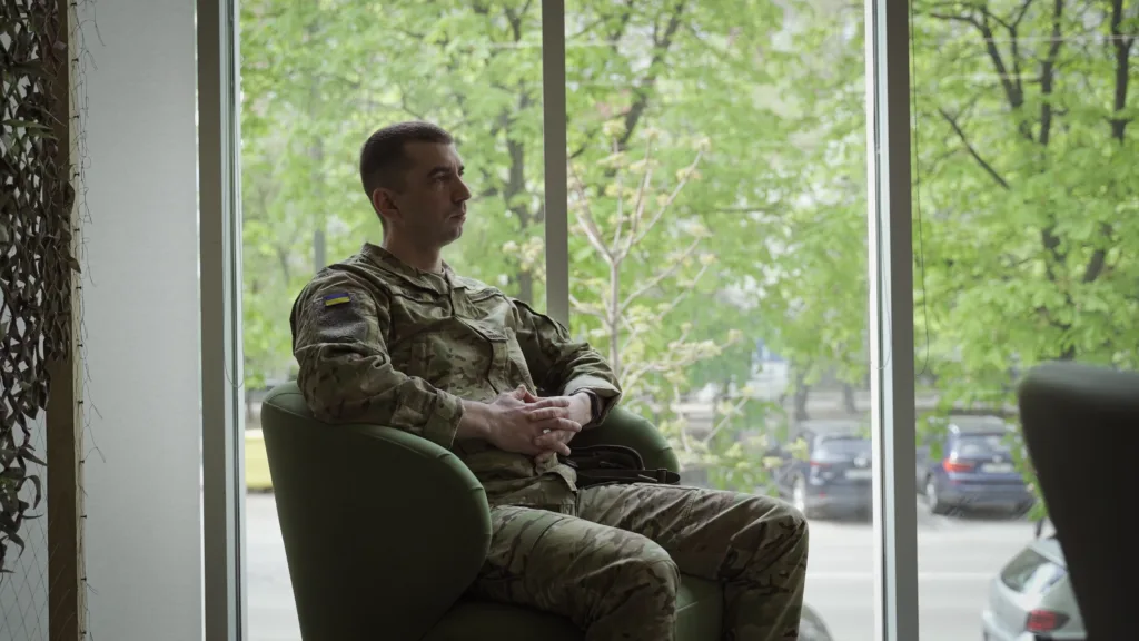 Військовий у камуфляжі сидить біля вікна