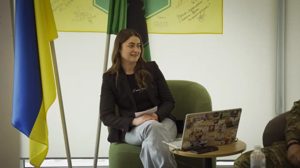 Жінка на зустрічі поруч з українським прапором