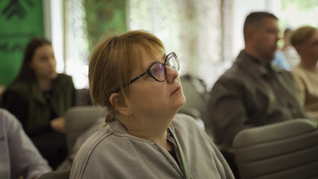 Жінка уважно слухає лекцію в аудиторії