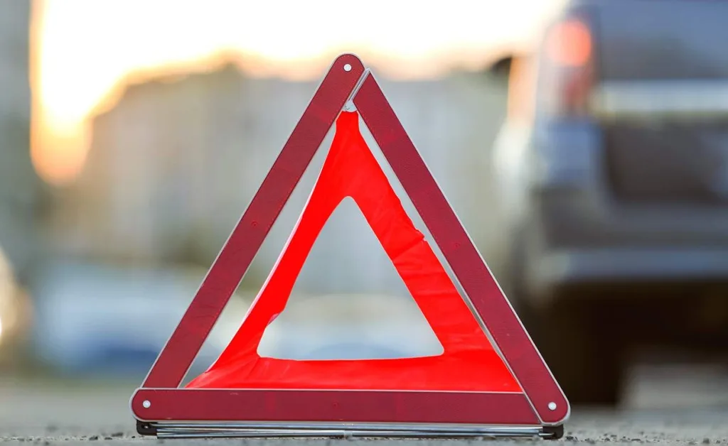 Червоний аварійний трикутник біля автомобіля