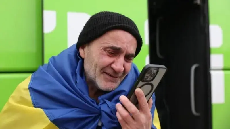 Чоловік у прапорі України дивиться на телефон