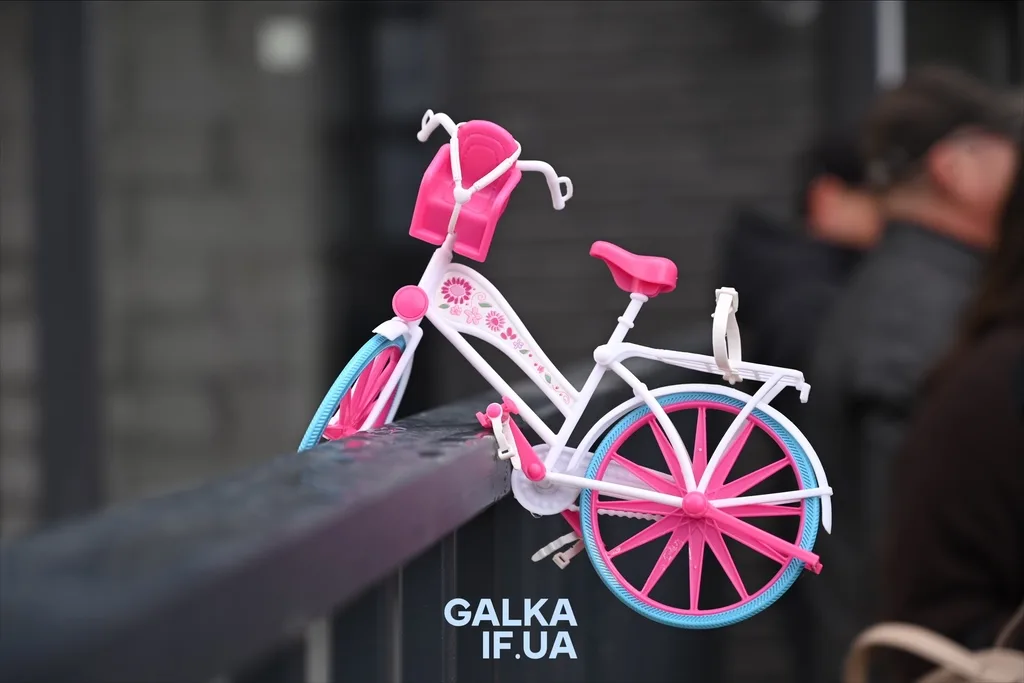 Дитячий рожево-білий велосипед на паркані