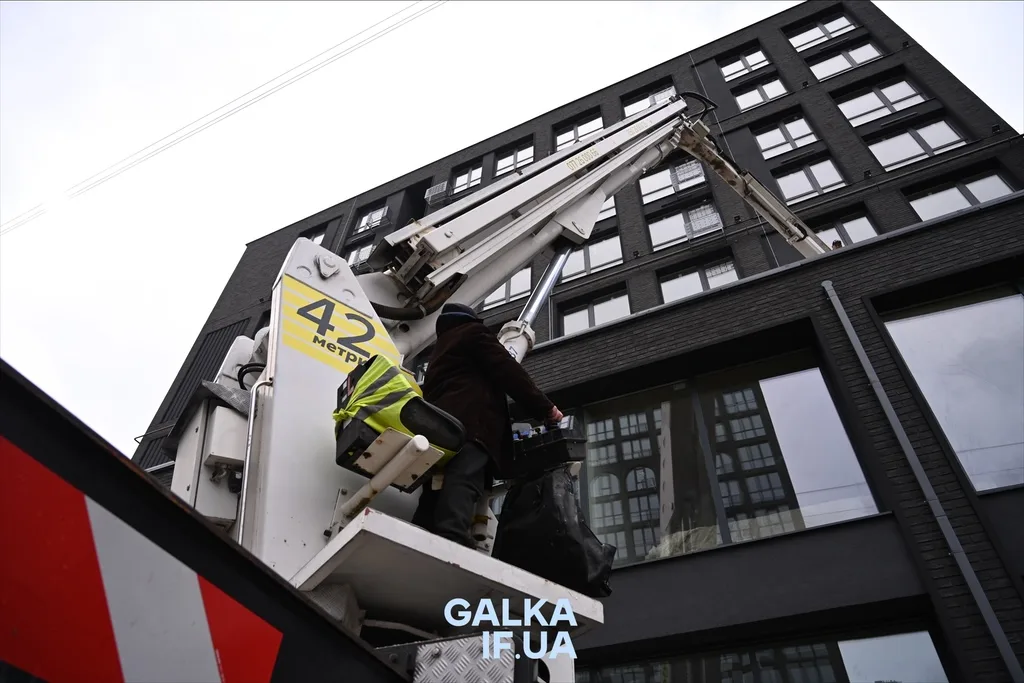 Робітник на підйомнику біля багатоповерхового будинку