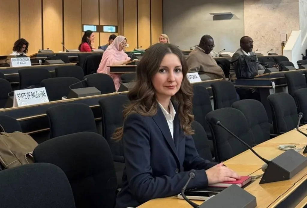 Жінка на міжнародній конференції сидить за столом