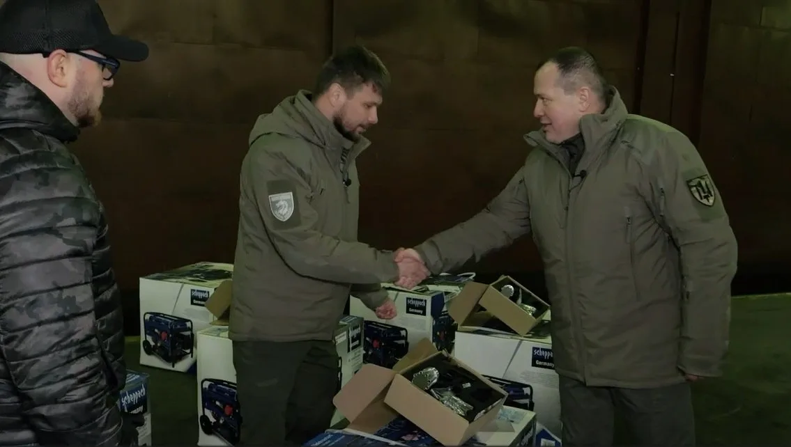 Люди тиснуть руки біля коробок з обладнанням