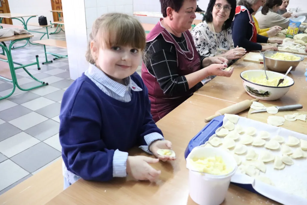 Діти та дорослі ліплять вареники разом на кухні