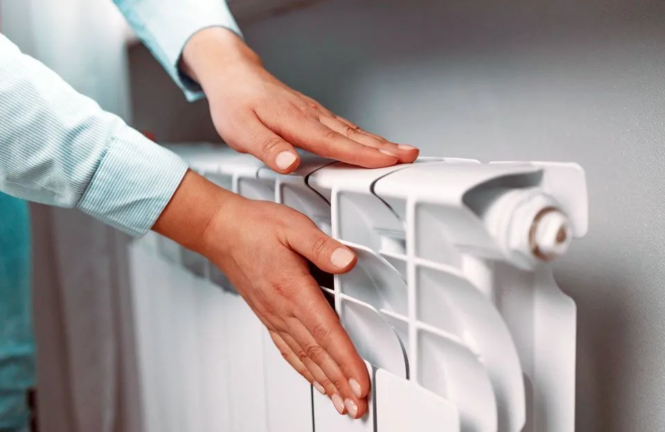 Людина перевіряє тепло батареї опалення
