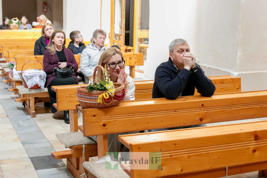 Люди моляться в церкві з великодніми кошиками