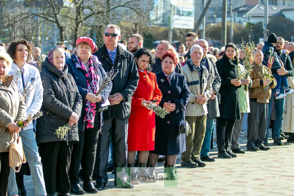 Люди стоять із вербовими гілками на вулиці