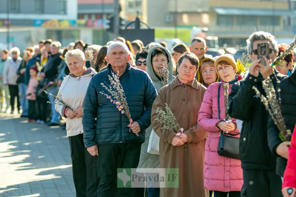 Люди стоять у черзі з вербовими гілками