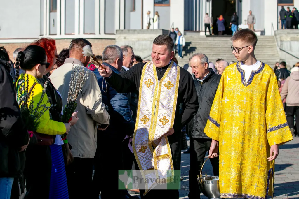 Священник благословляє людей на площі біля церкви