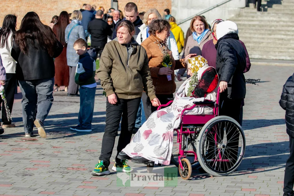 Люди спілкуються на вулиці, жінка у візку