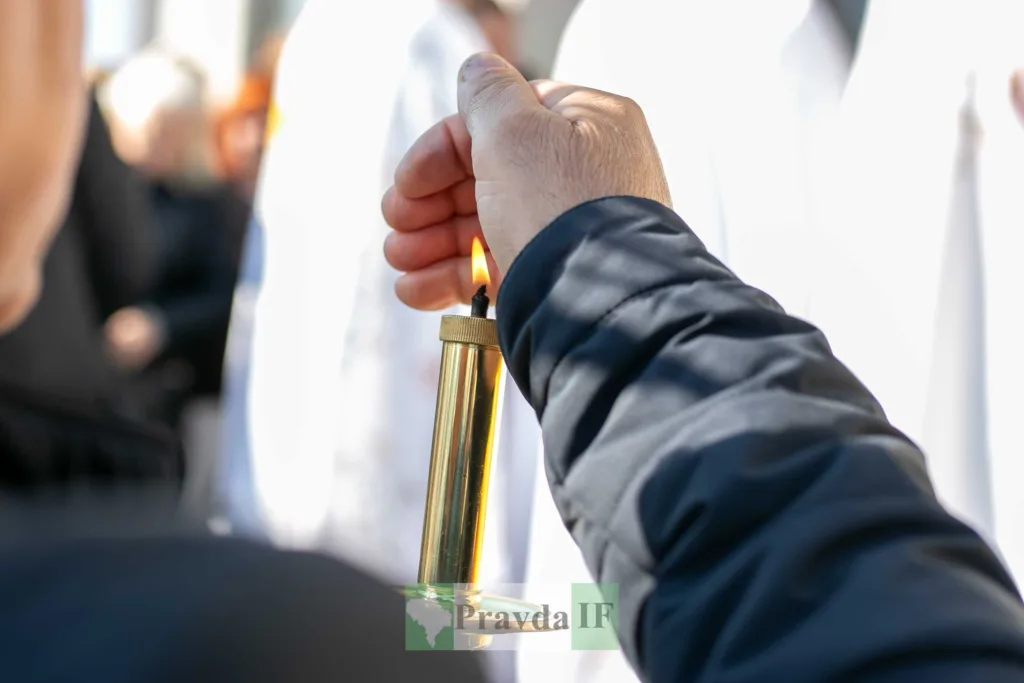 Людина тримає запалену свічку під час церемонії