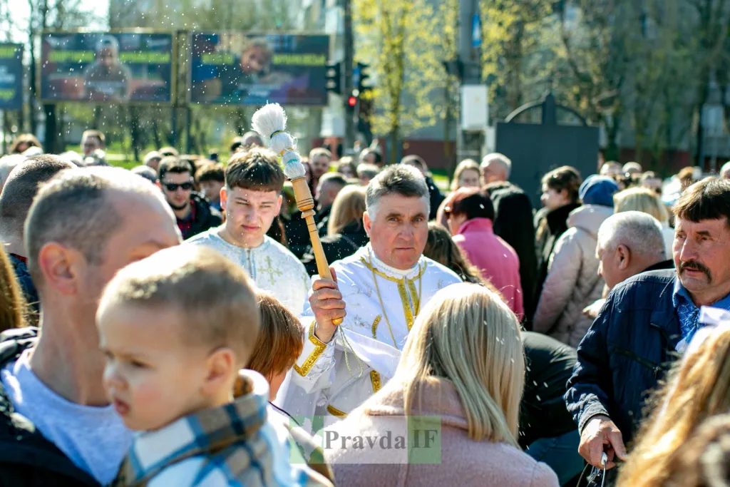 Священник освячує людей освяченою водою на вулиці