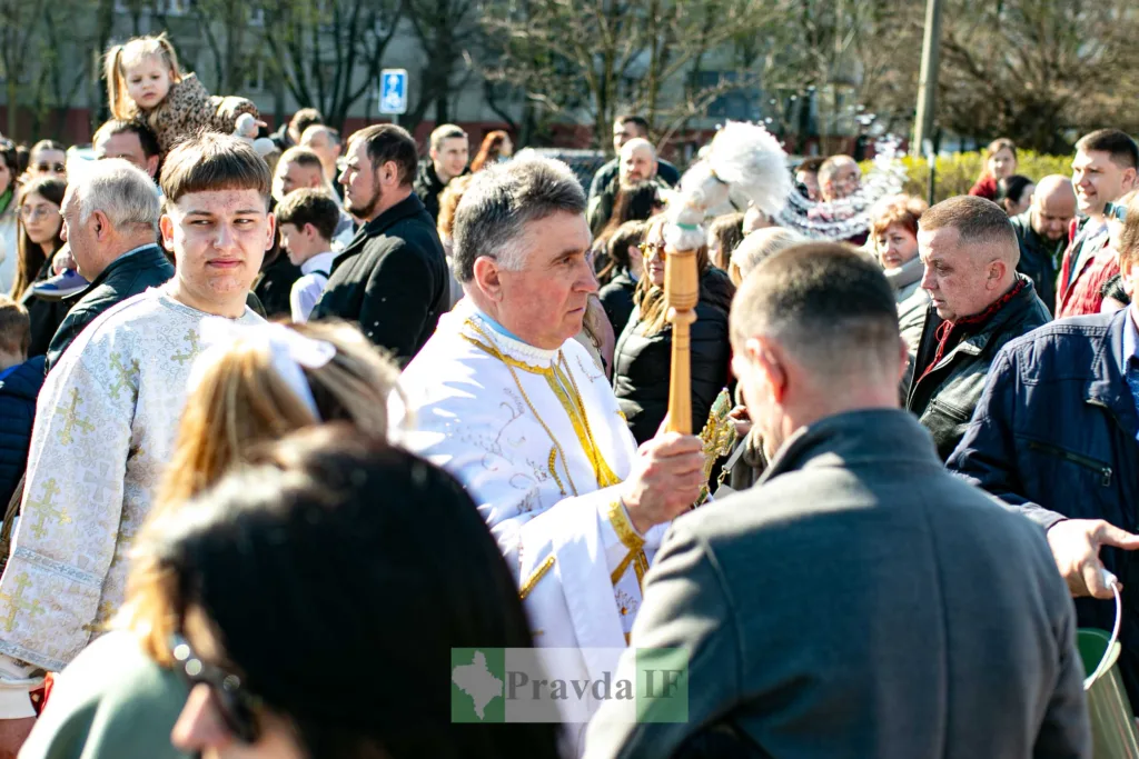 Священник окроплює вірян святою водою на подвір’ї