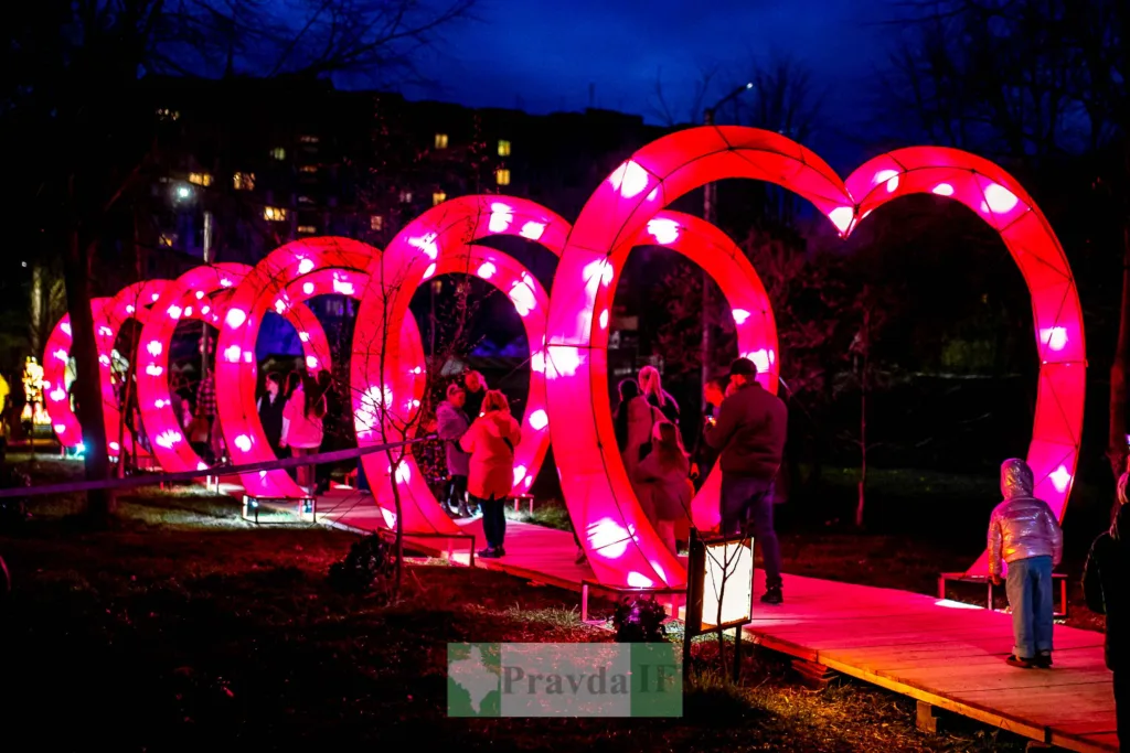 Люди проходять крізь світлові арки у формі сердець