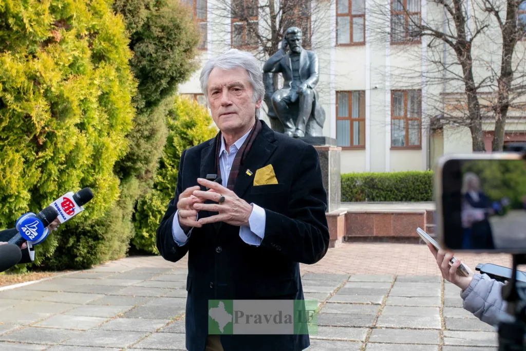 Чоловік дає інтерв'ю перед пам’ятником на вулиці