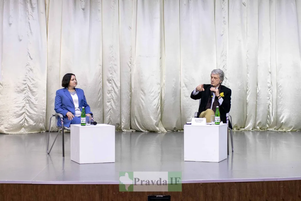 Двоє людей обговорюють на сцені перед завісою