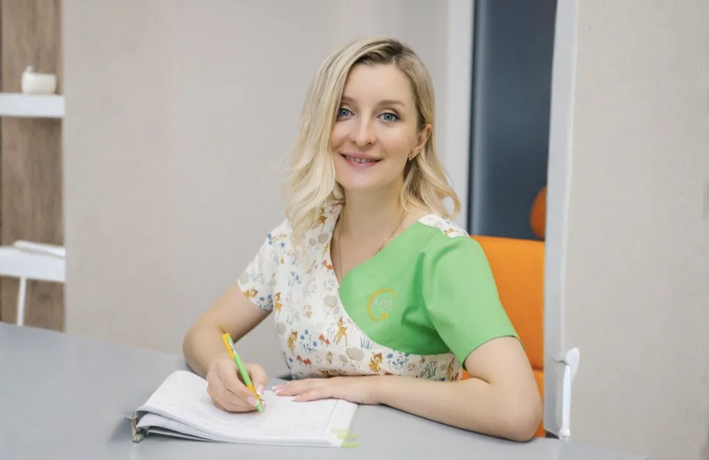 Жінка у зеленій формі пише у зошиті