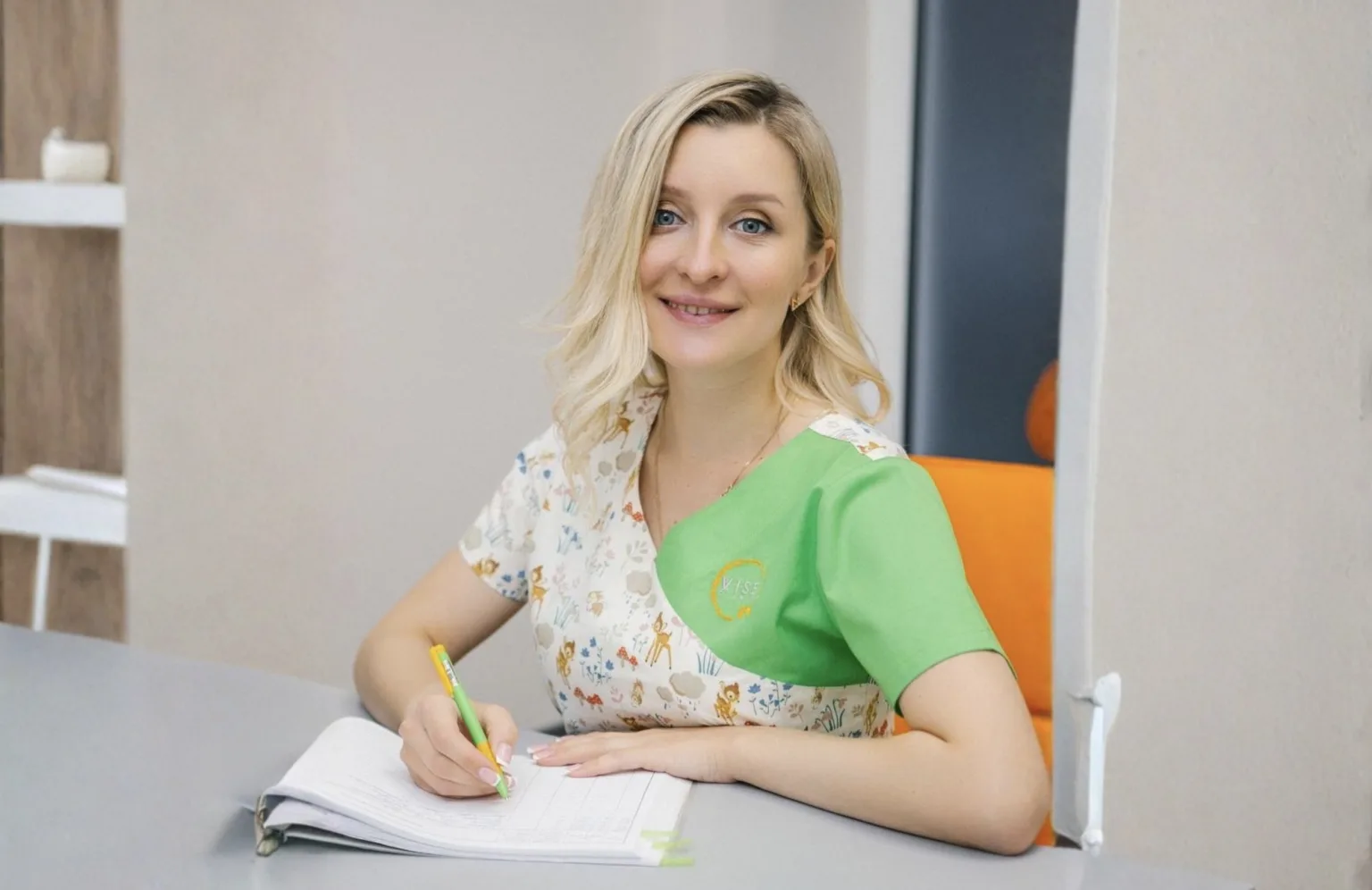 Жінка у зеленій формі пише у зошиті