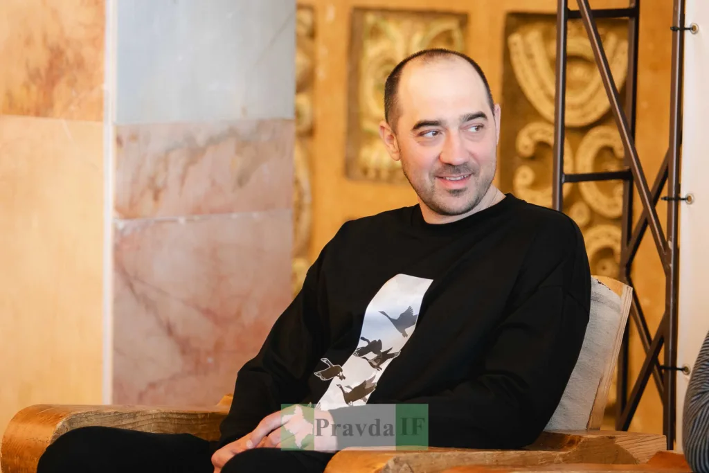 Чоловік сидить і посміхається в приміщенні