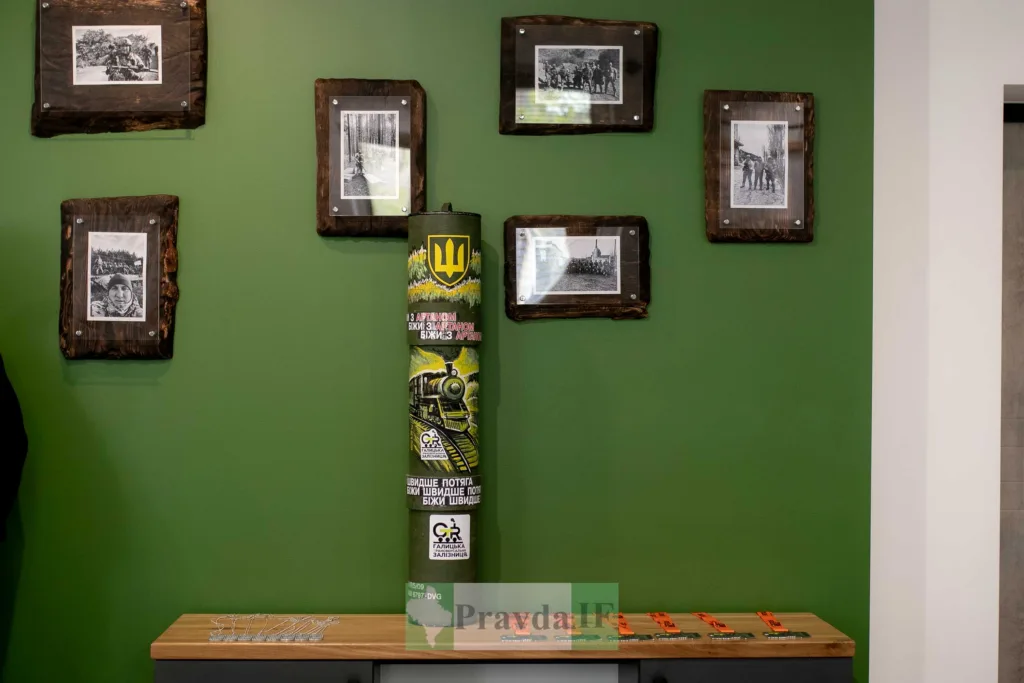 Зелена стіна з фотографіями та декоративним циліндром