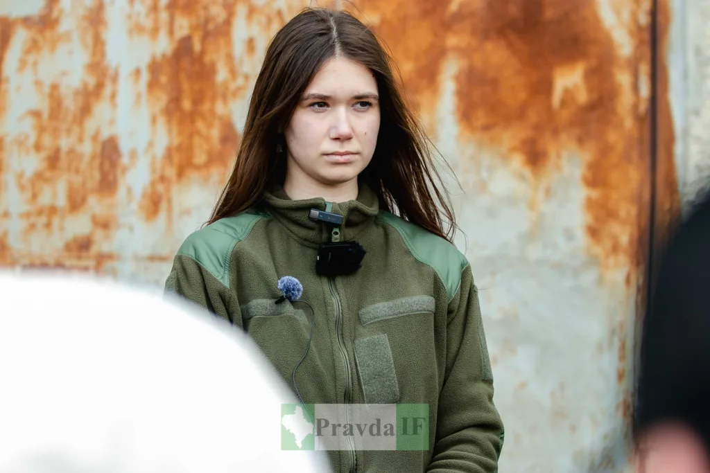 Дівчина у військовій формі стоїть надворі