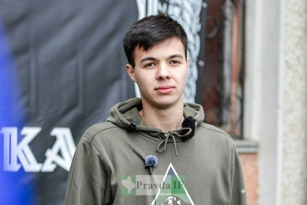 Молодий чоловік у зеленій толстовці на вулиці