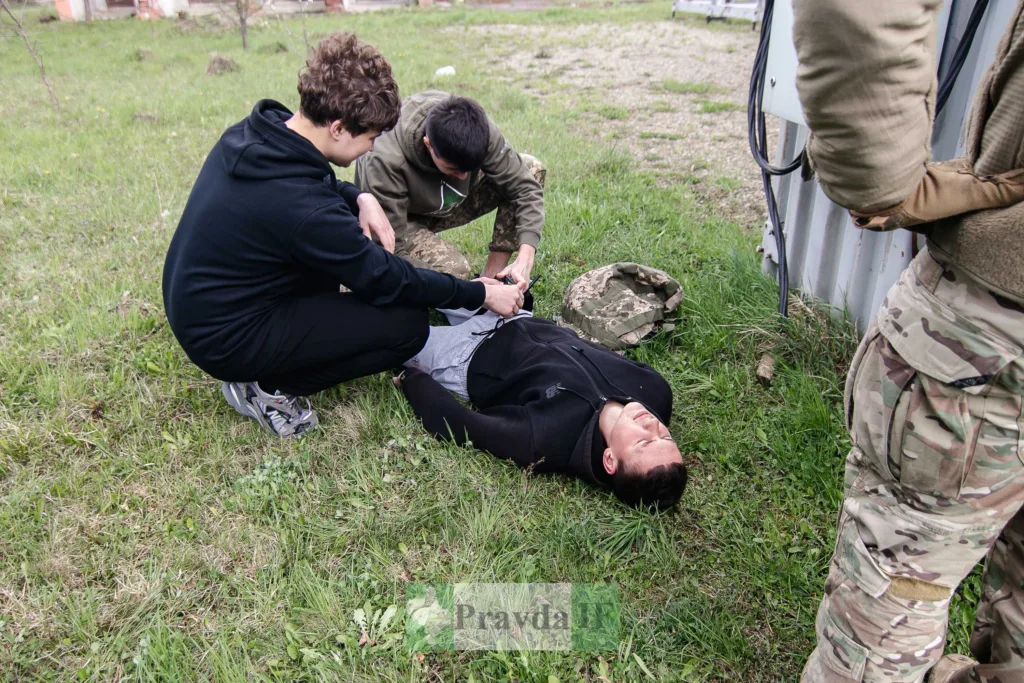 Надання першої допомоги пораненому на траві