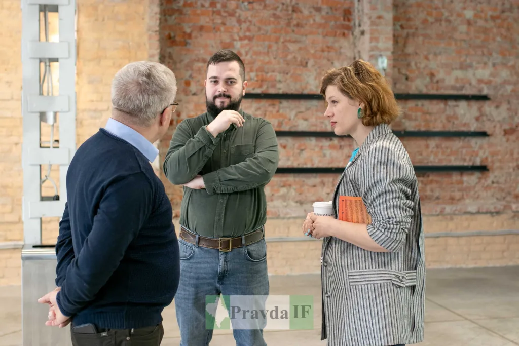 Троє людей розмовляють у просторому приміщенні