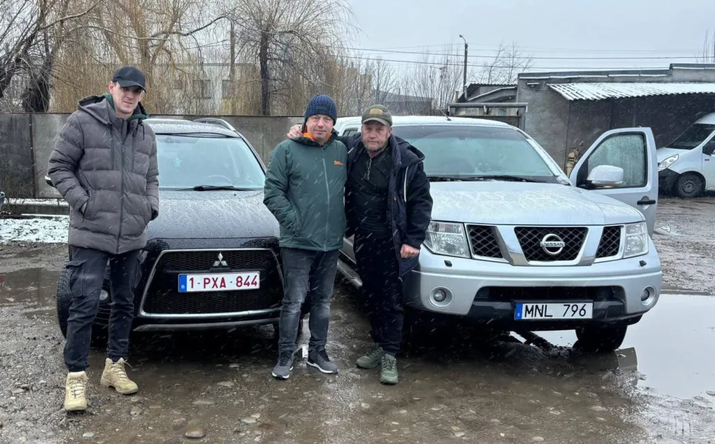 Троє чоловіків стоять біля автомобілів Mitsubishi і Nissan