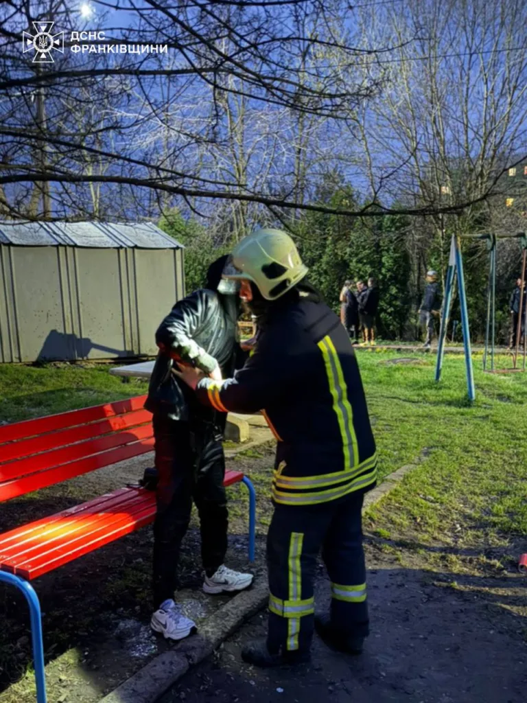 Рятувальник допомагає людині в парку біля лавки