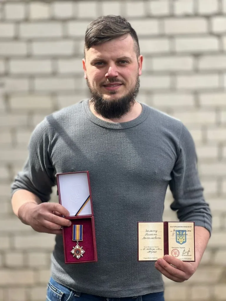 Чоловік тримає медаль і посвідчення нагороди України