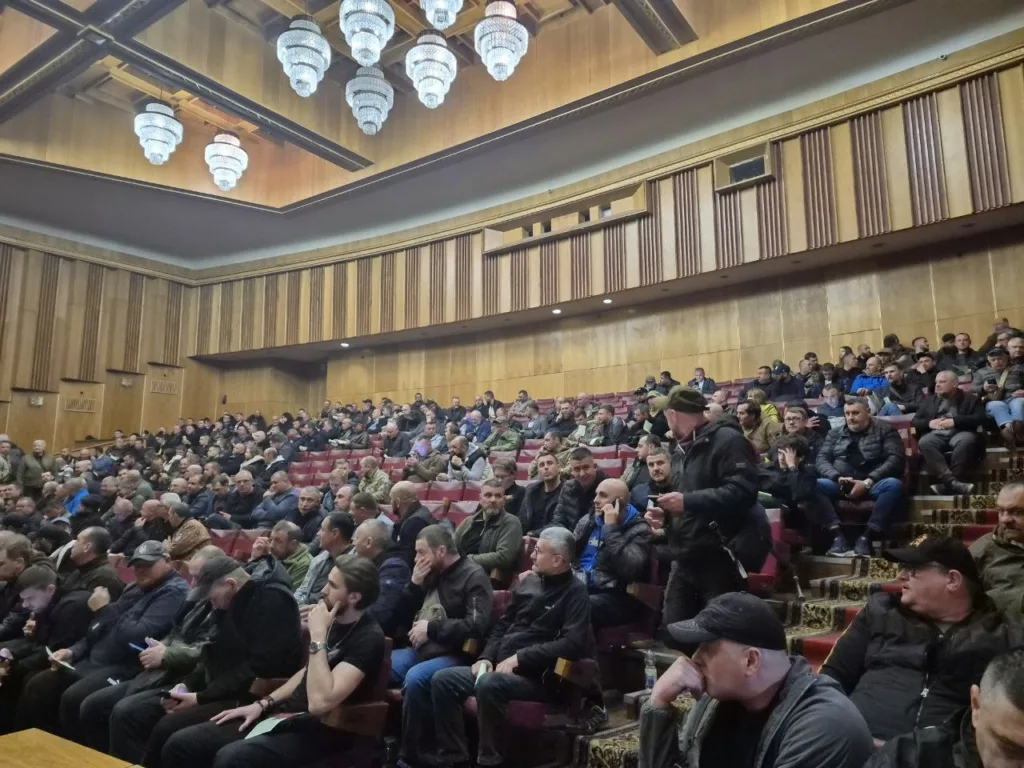 Люди сидять у великій залі під час зборів