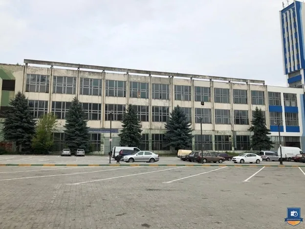 Велика промислова будівля з припаркованими автомобілями