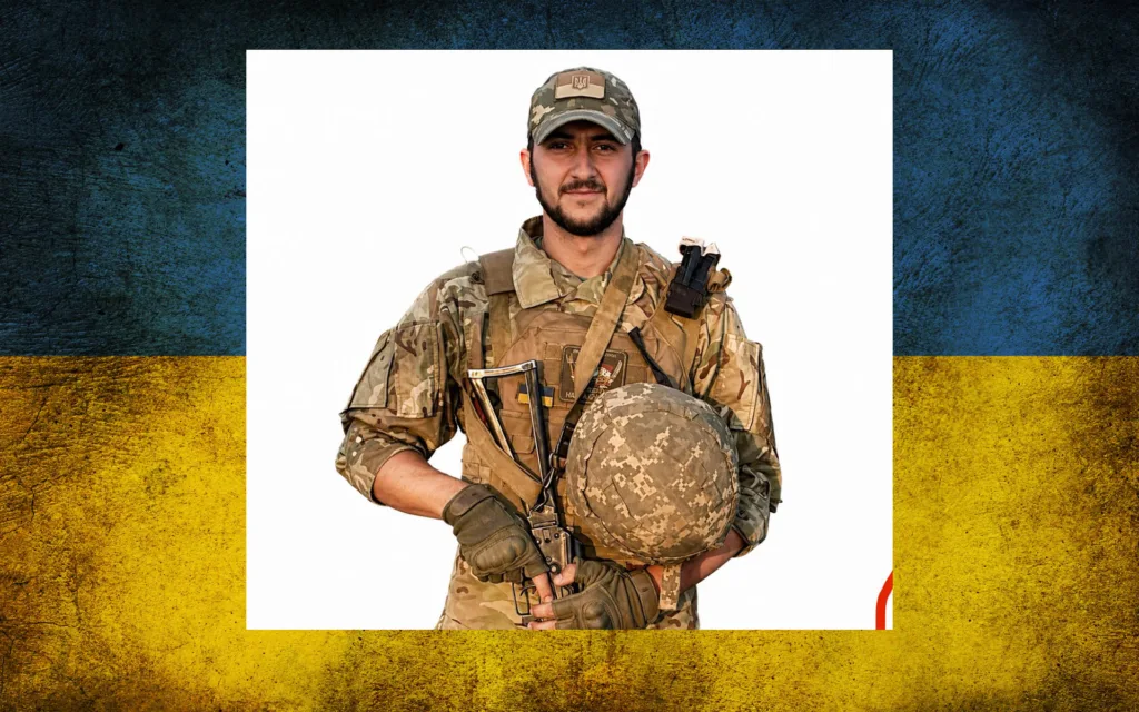 Український військовий у формі перед прапором України