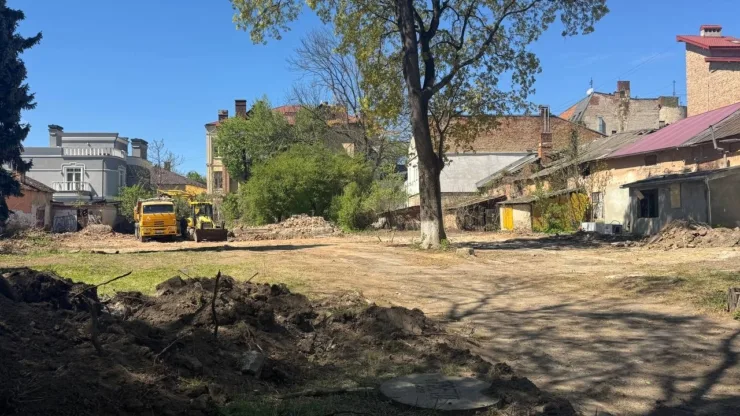 Будівельна техніка на подвір’ї між старими будинками